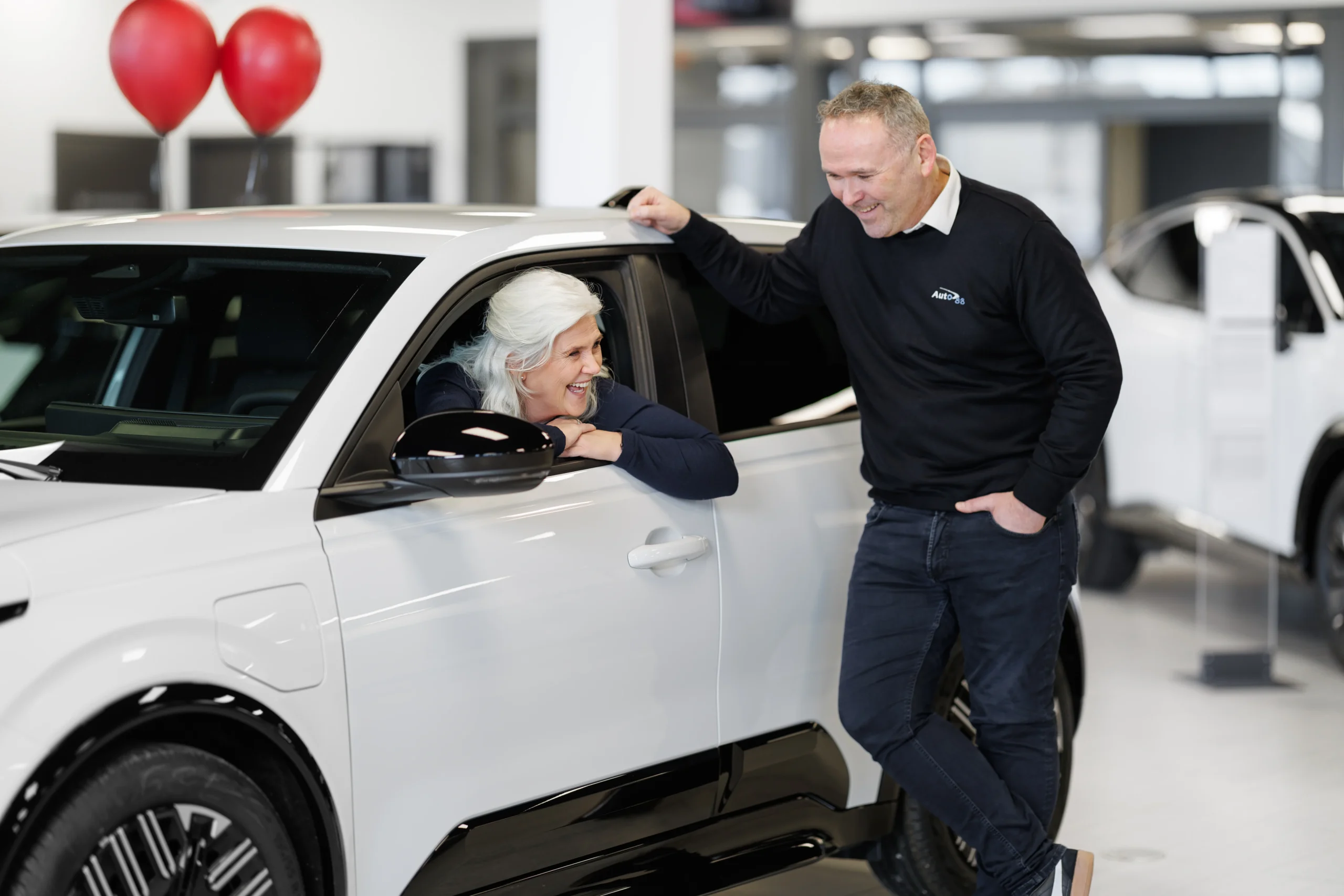 Bil og to personer som smiler og ler