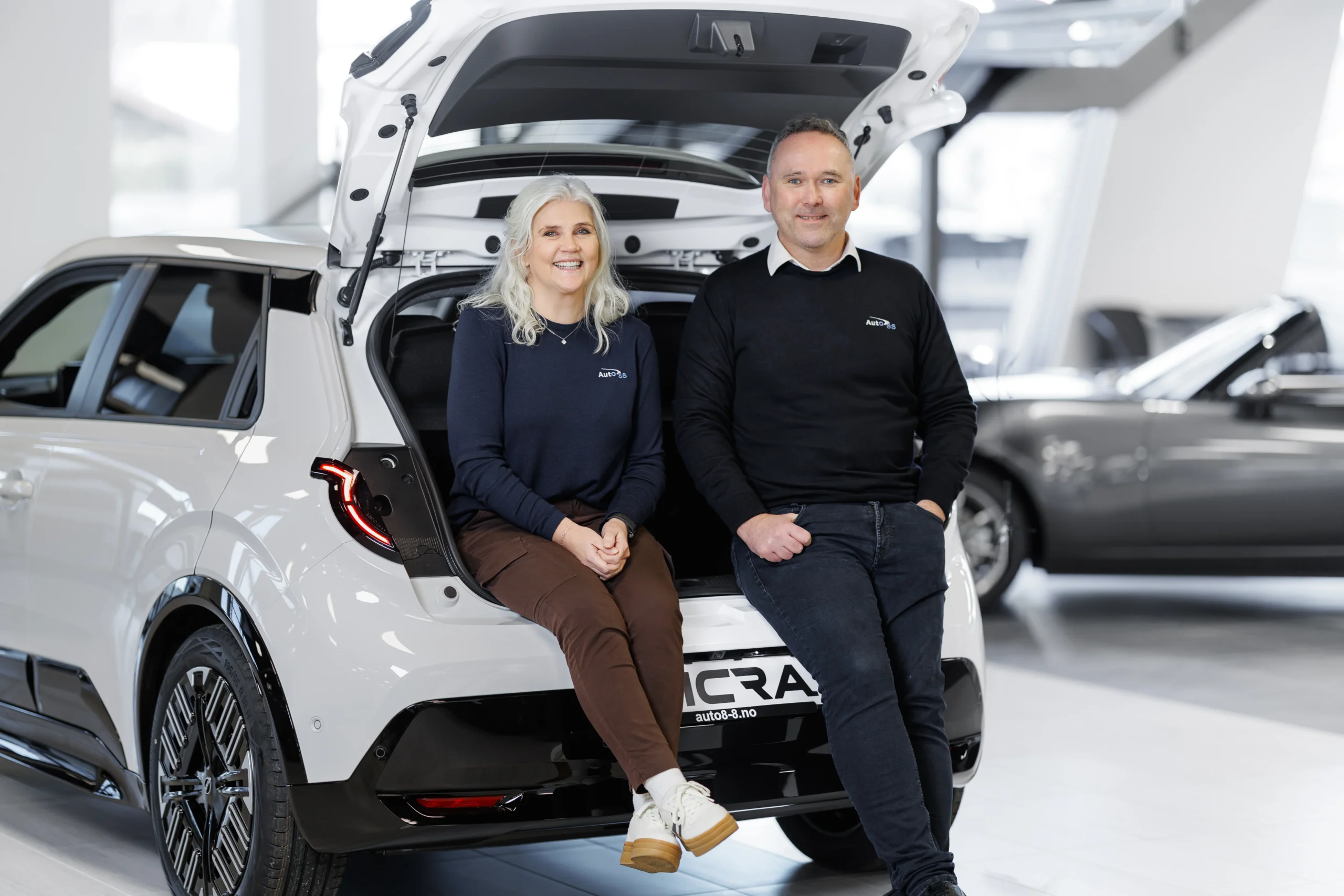 To personer i bagasjerommet på en hvit bil