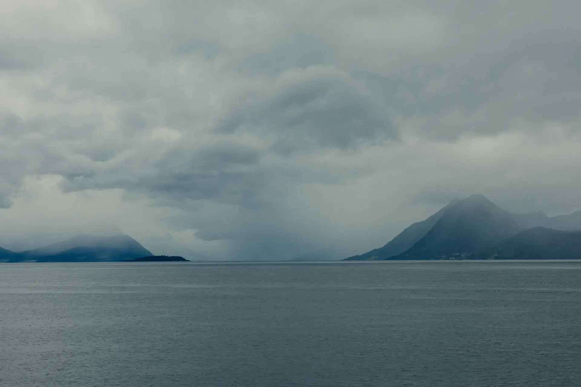 Fjord under tunge stormskyer mellom fjell på Vestlandet.