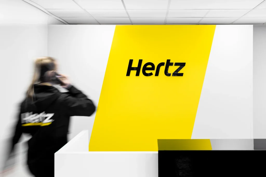 Hertz-ansatt med telefon foran resepsjonsveggen ved Atlantic Mobility