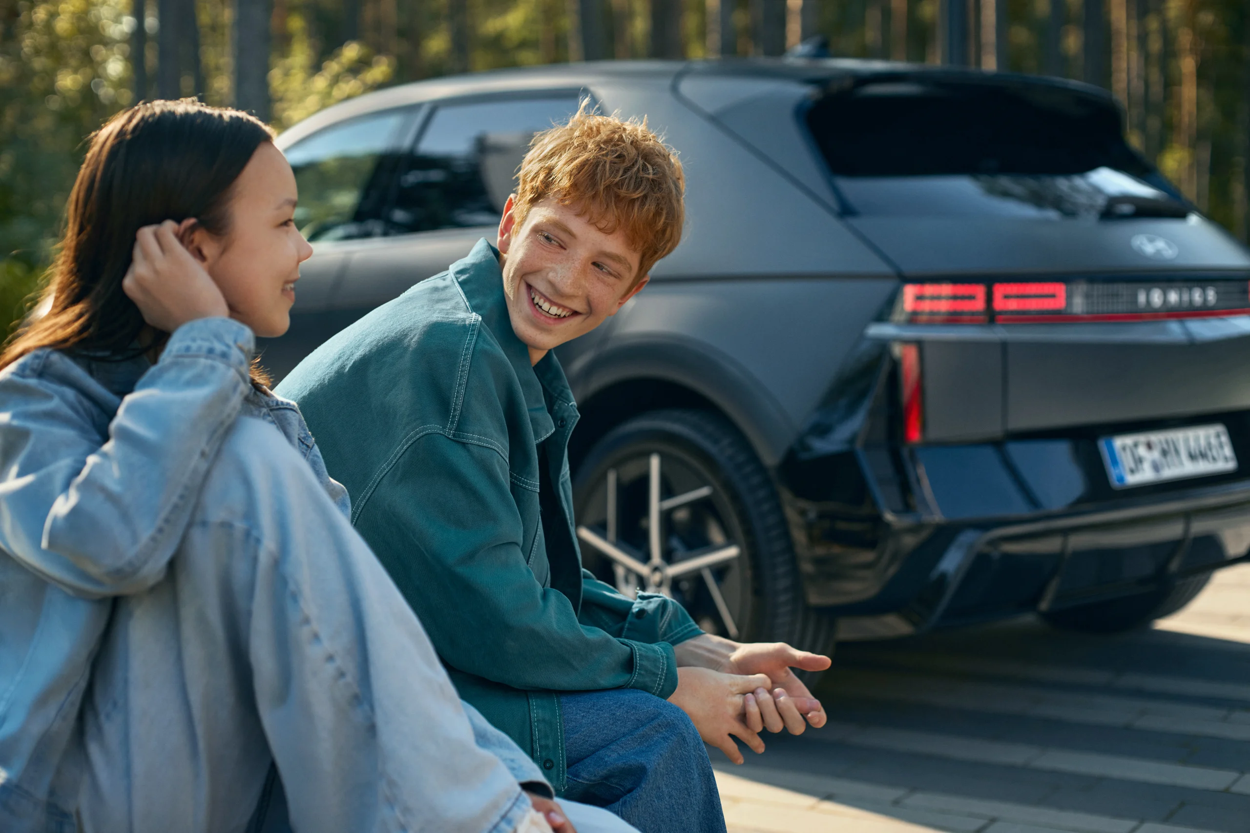 Hyundai IONIQ 5 sett skrått bakfra med to personer ved siden av