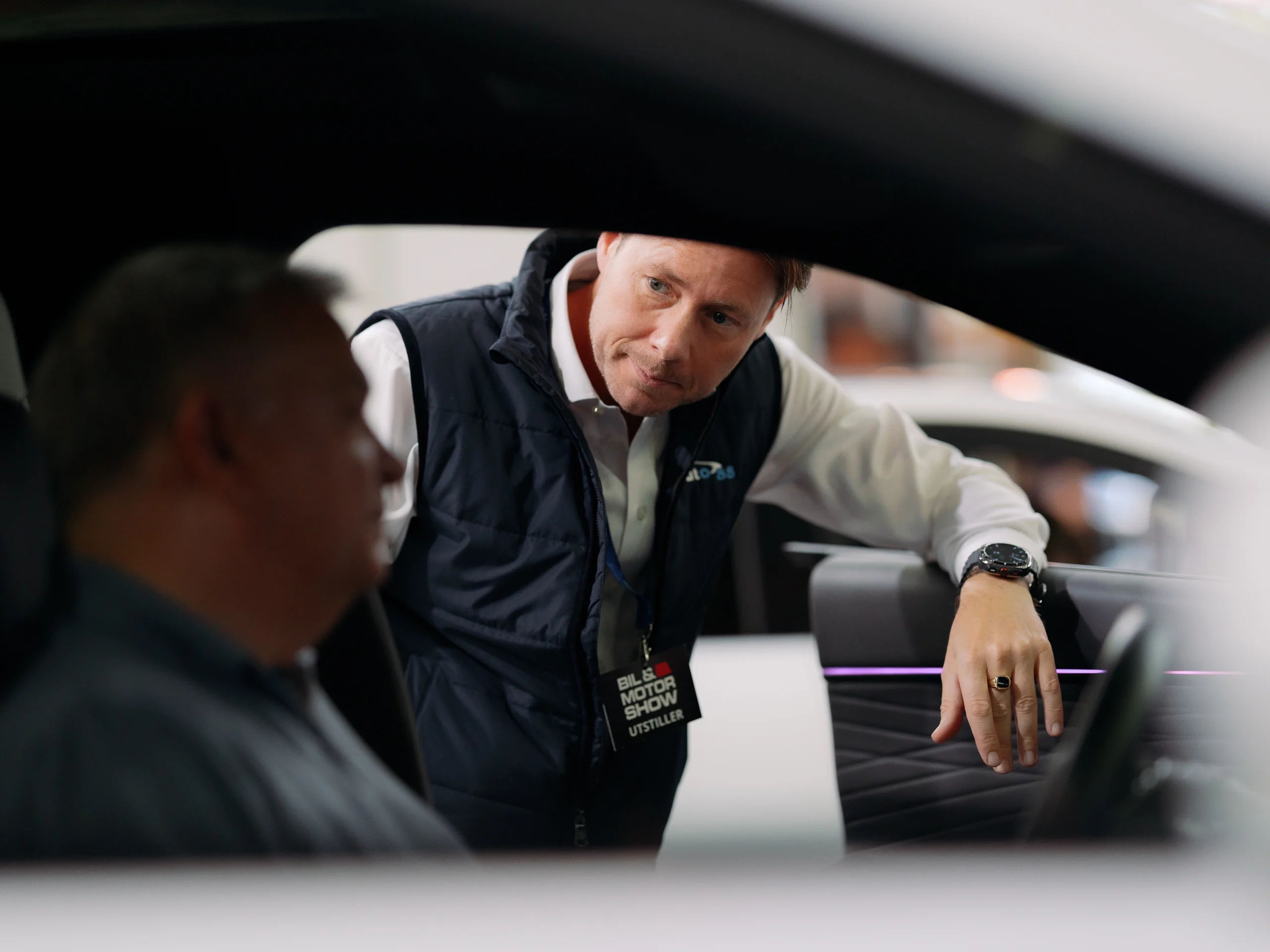 En selger fra Auto 8-8 viser fram interiøret i Exlantix ET til en besøkende på messa