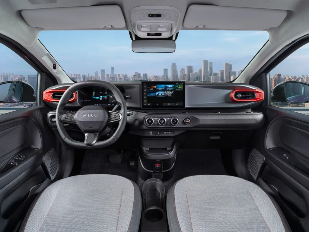 Interiøret i Nissan Pixo med ratt, digitalt instrumentpanel og skjerm midt på dashbordet.